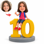 Personalisierte Wackelkopf-Figur für Mädchen zum 10. Geburtstag, sitzend auf der Zahl 10